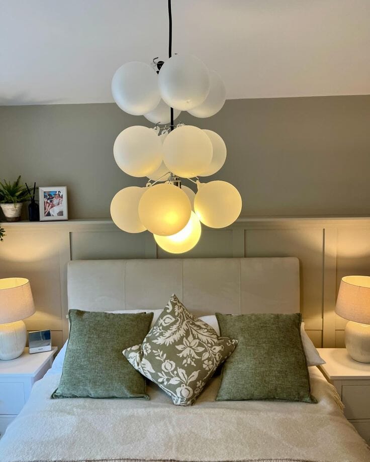 Grey bed with sage decorate pillows and fabulous ceiling light